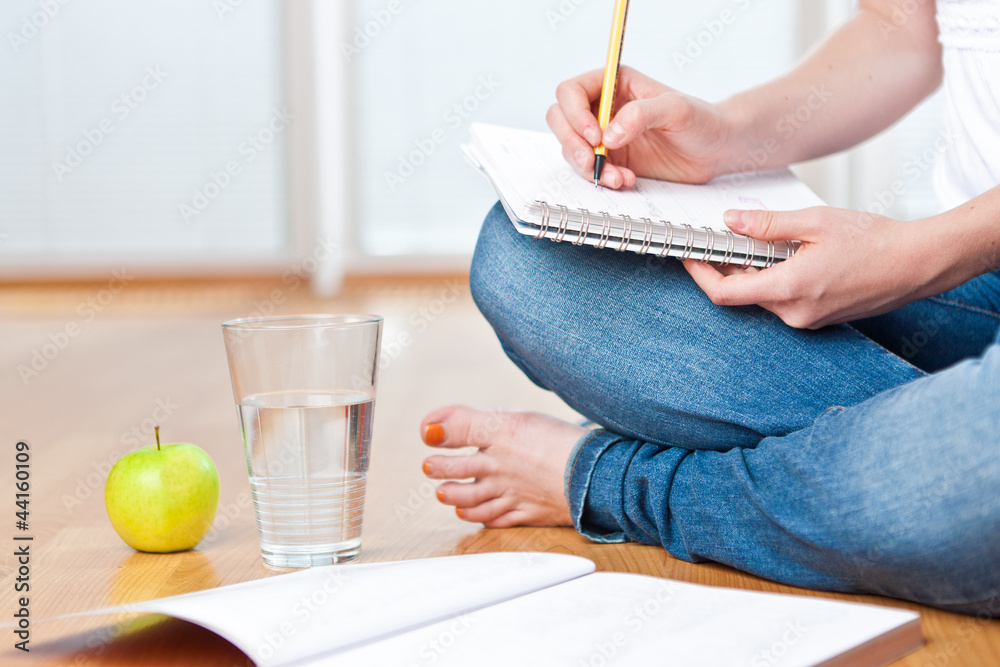 © listercz - Closeup of young female student sitting on the floor and taking