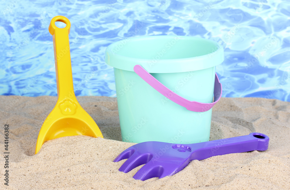 Children's beach toys on sand on water background Children's beach toys on sand on water background