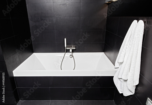 White square bathtub in modern black and white bathroom interior