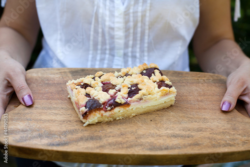 Prune fruit cake on wooden plate with hands
