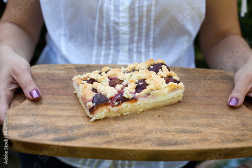 Plum cake on wooden plate with hands
