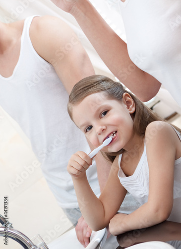 Little girl brushes her teeth in bathroom