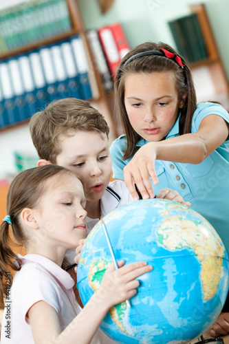 Cllassmates help to each other to find something at the globe