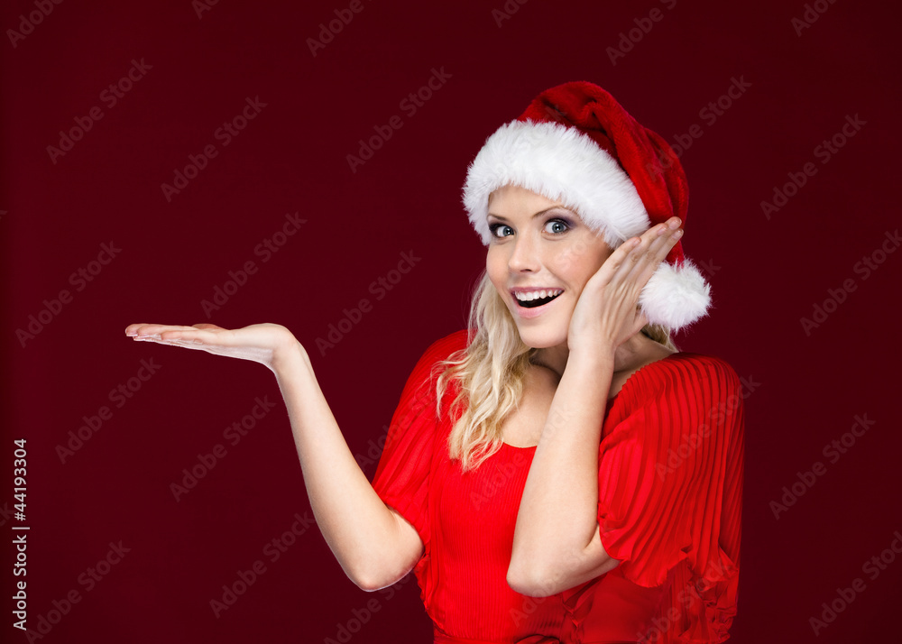 Woman in Christmas cap gestures palm up, isolated on purple Woman in Christmas cap gestures palm up, isolated on purple