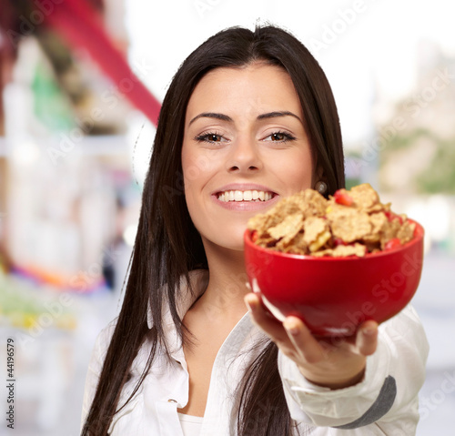 portrait of young woman offering cereals bowl at street