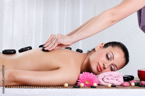 Beautiful woman receiving hotstone massage at spa