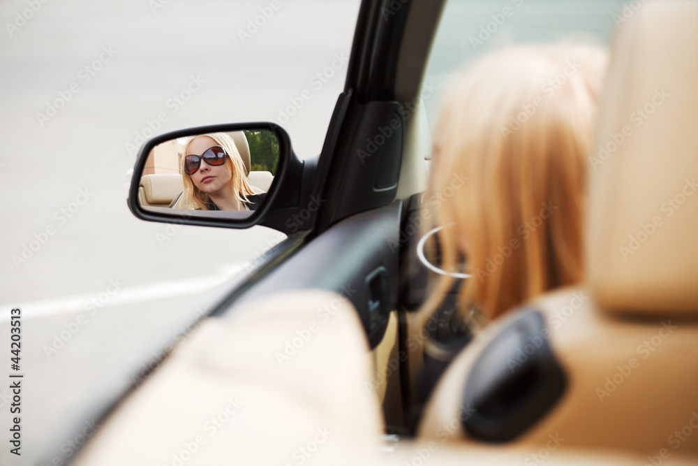 Young woman looking in the car mirror