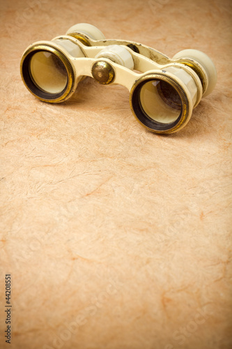 Old binoculars on vintage paper background