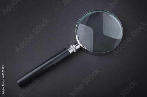 Closeup of magnifying glass on dark surface