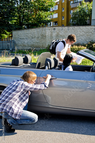 Male thief opening car door, accomplice distracts female photo