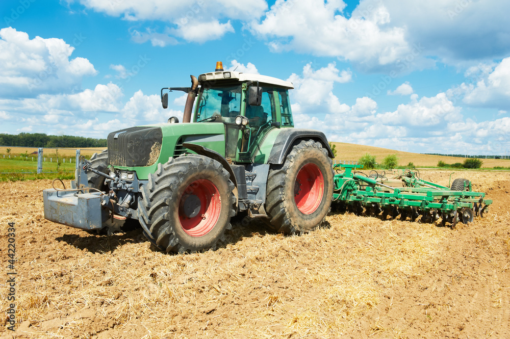 Fototapeta premium Ploughing tractor at field cultivation work