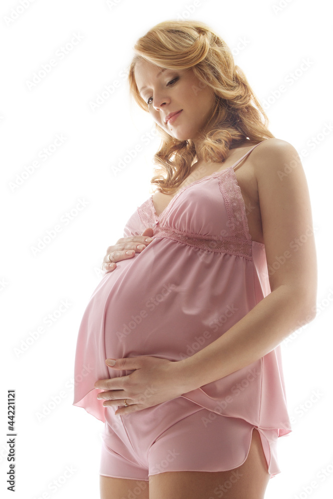 Pregnant woman smiling, looking at belly, embracing belly. Pink Pregnant woman smiling, looking at belly, embracing belly. Pink