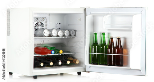 Mini fridge full of bottles of alcoholic beverages isolated