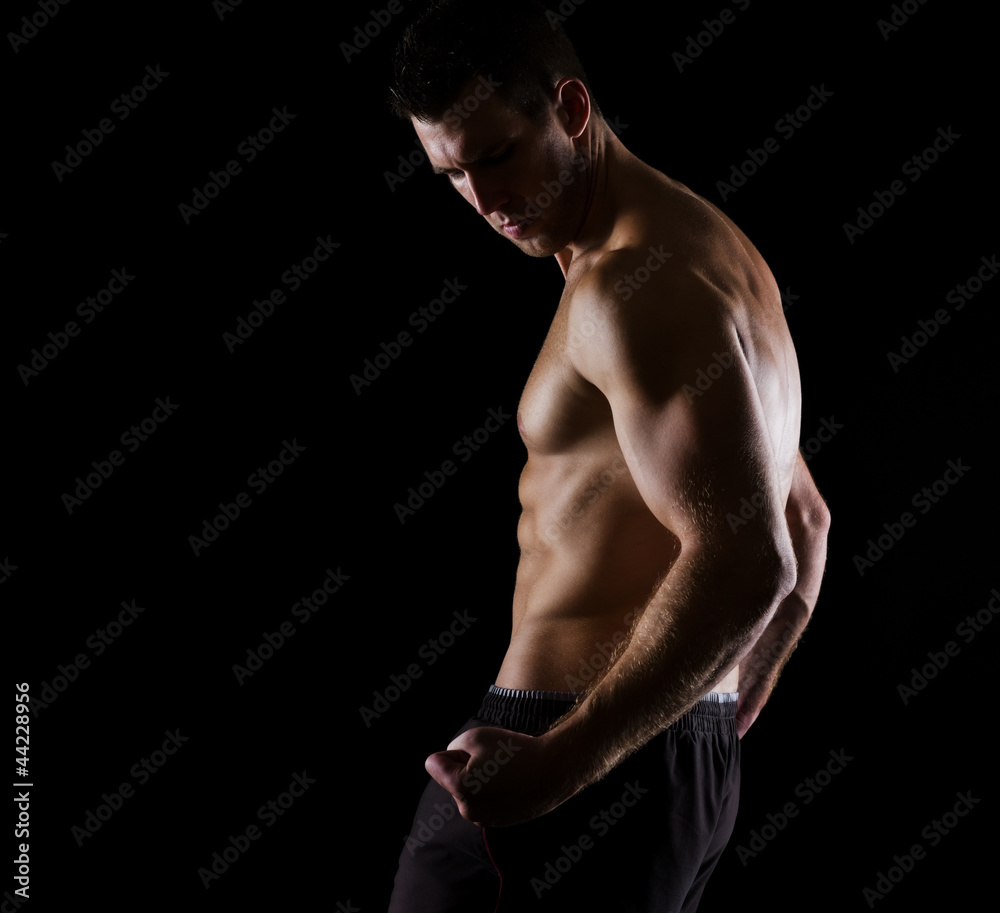 Strong muscular athlete posing on black