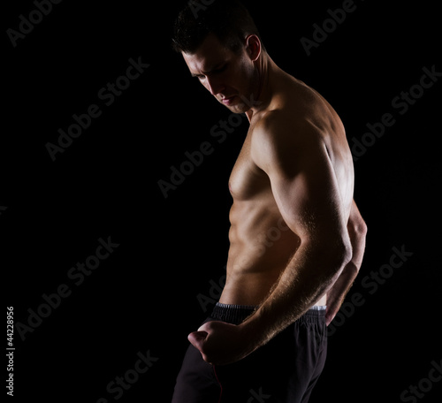 Strong muscular athlete posing on black © Alliance
