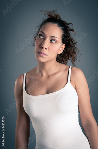 Portrait of suspicious brunette curly girl with white vest on da
