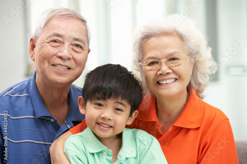 Portrait Of Chinese Grandparents With Grandson Relaxing At Home © Monkey Business