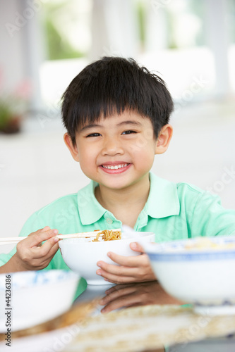 Young Chinese Boy Sitting At Home Eating Meal