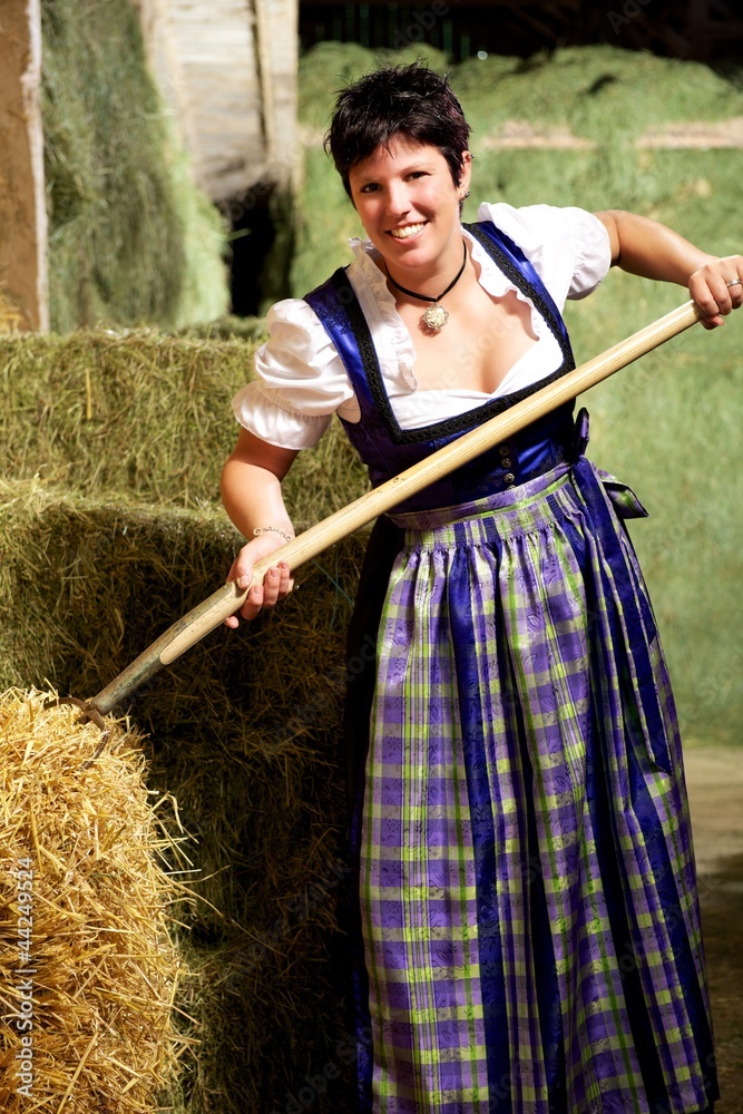 Fototapeta premium Frau im Dirndl mit Heugabel im Stadel