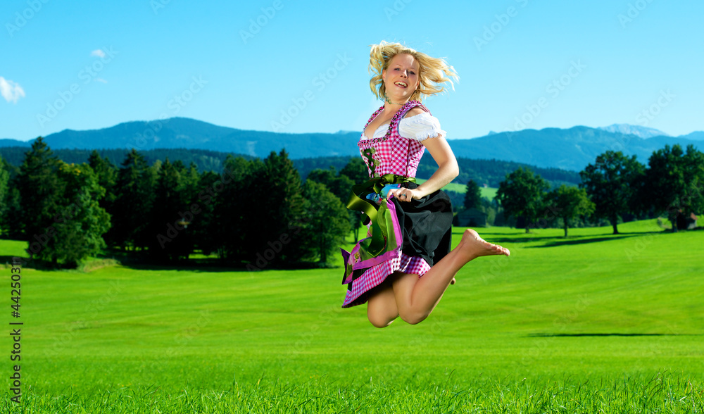 Frau im Dirndl spring auf Wiese Frau im Dirndl spring auf Wiese