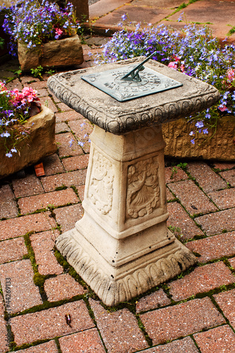 ornamental sundial in a small paved garden photo