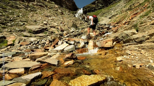 hiker crossing stream photo