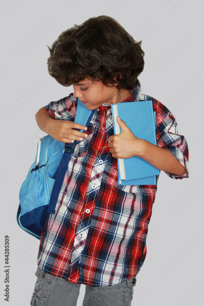 A beautiful schoolboy with blue bag, isolated on grey background