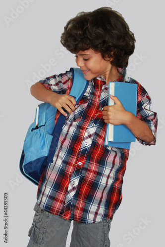 A beautiful schoolboy with blue bag, isolated on grey background photo