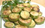 Fried zucchini slices with parsley on white plate closeup