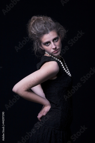 beautiful young woman with elegant black dress, on black