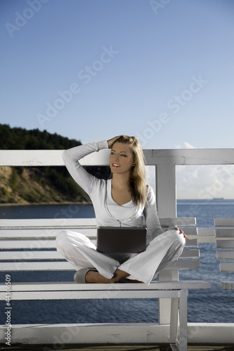 Young woman with a laptop on the pier