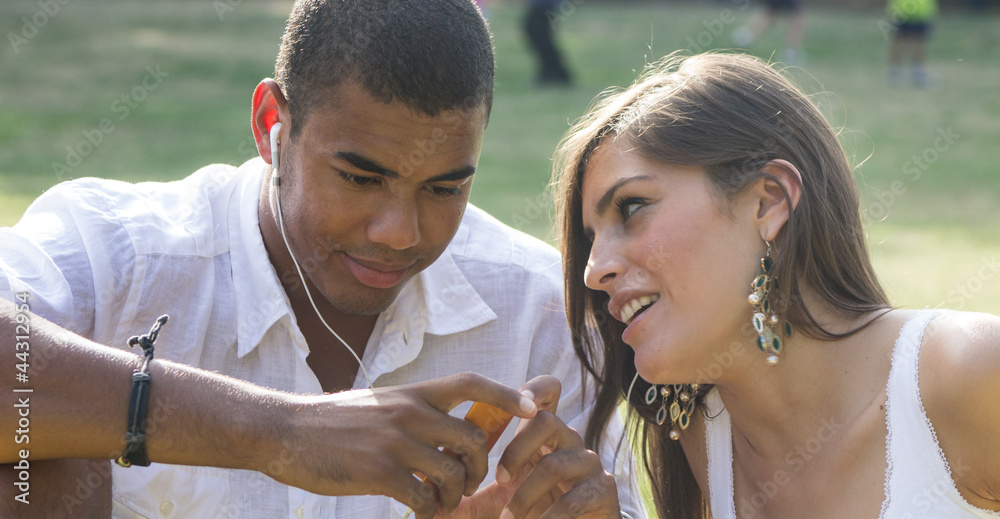 Young couple flirting in a relaxing garden, playing a mp3