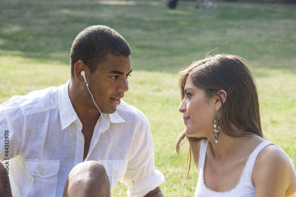 Young couple flirting in a relaxing garden, playing a mp3