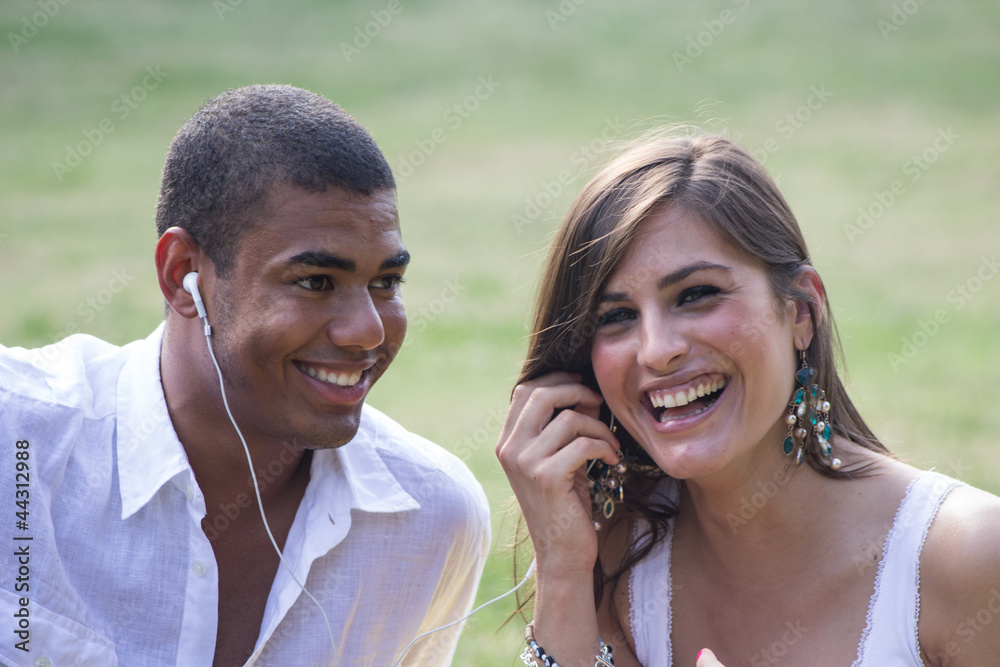 Young couple flirting in a relaxing garden, playing a mp3