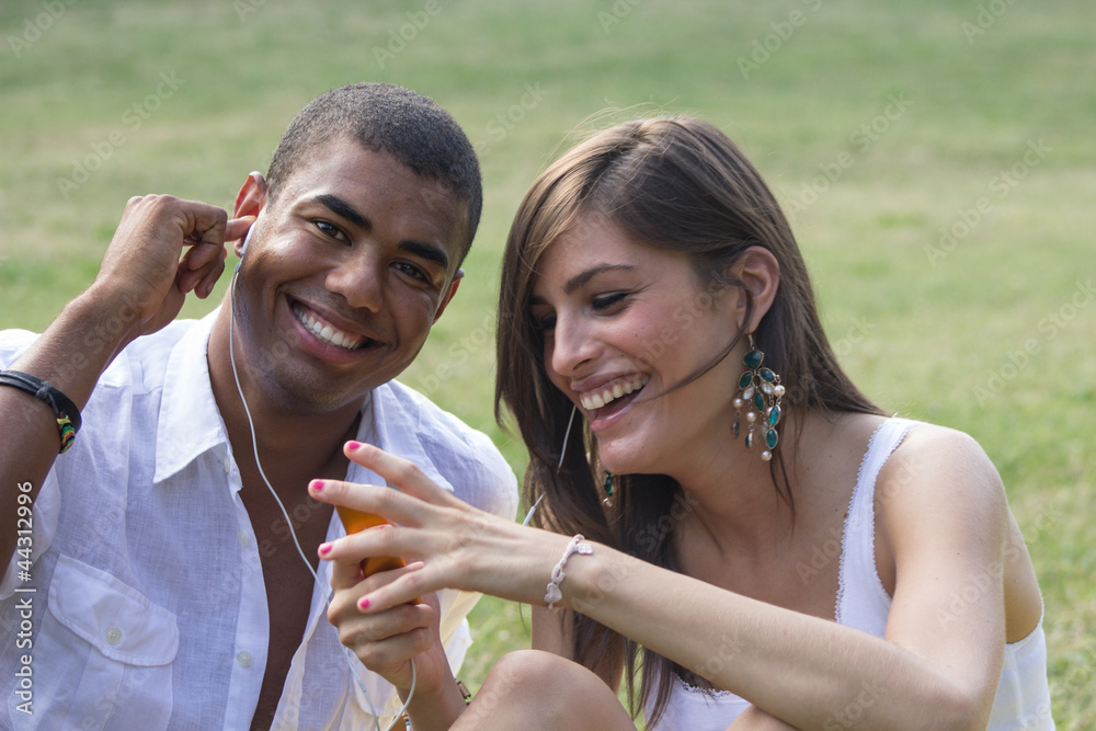 Young couple flirting in a relaxing garden, playing a mp3
