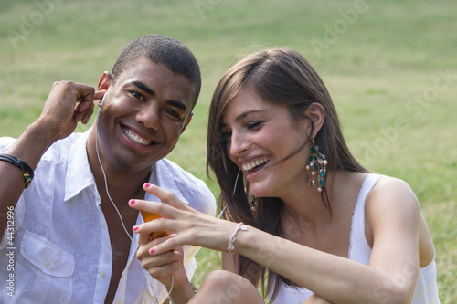 Young couple flirting in a relaxing garden, playing a mp3 photo