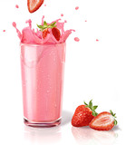 Strawberries splashing into a milkshake glass, with two others o