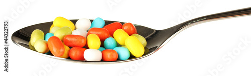 colorful pills on spoon on white background close-up
