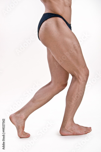 muscled legs of a male athletic model on white background