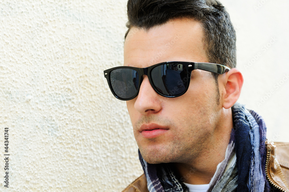 Attractive man wearing tinted sunglasses in urban background Attractive man wearing tinted sunglasses in urban background