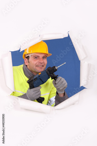 Manual worker with drill tearing through poster photo