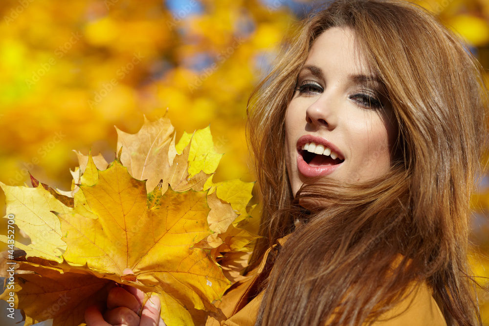 Young woman with autumn leaves in hand and fall yellow maple gar Young woman with autumn leaves in hand and fall yellow maple gar