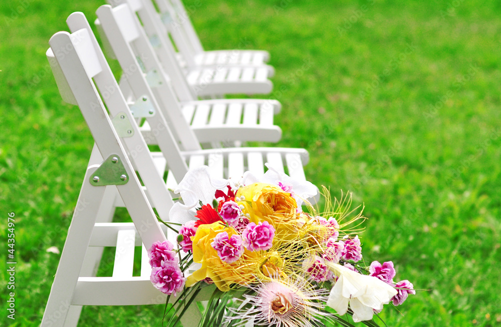 A number of white chairs and a bouquet of flowers.