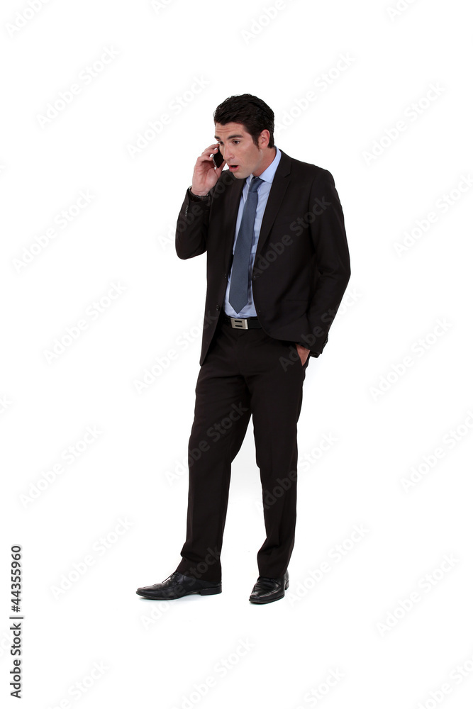 Businessman receiving shocking news over the telephone Businessman receiving shocking news over the telephone