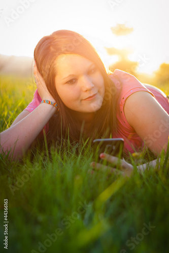 Teenage girl texting on her smartphone outdoors