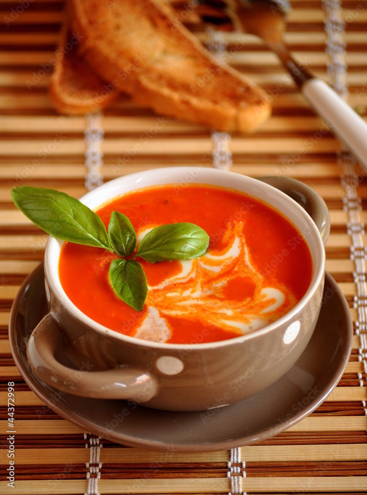 Soup of tomato with cream and a basil leaf