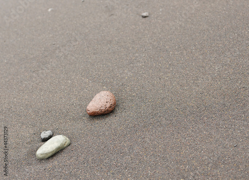 Abstract background with pebbles on black volcanic sand