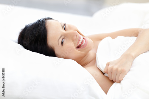 Laughing woman tries to fall asleep lying on the pillow