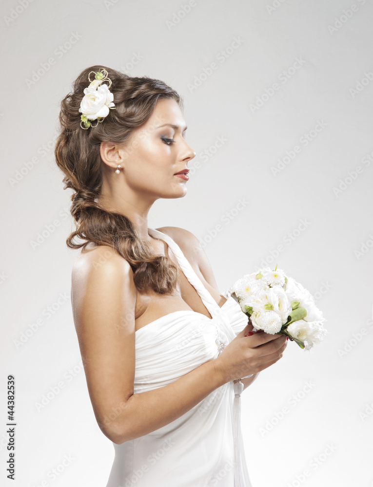 A young Caucasian bride in white clothes holding a bouquet A young Caucasian bride in white clothes holding a bouquet