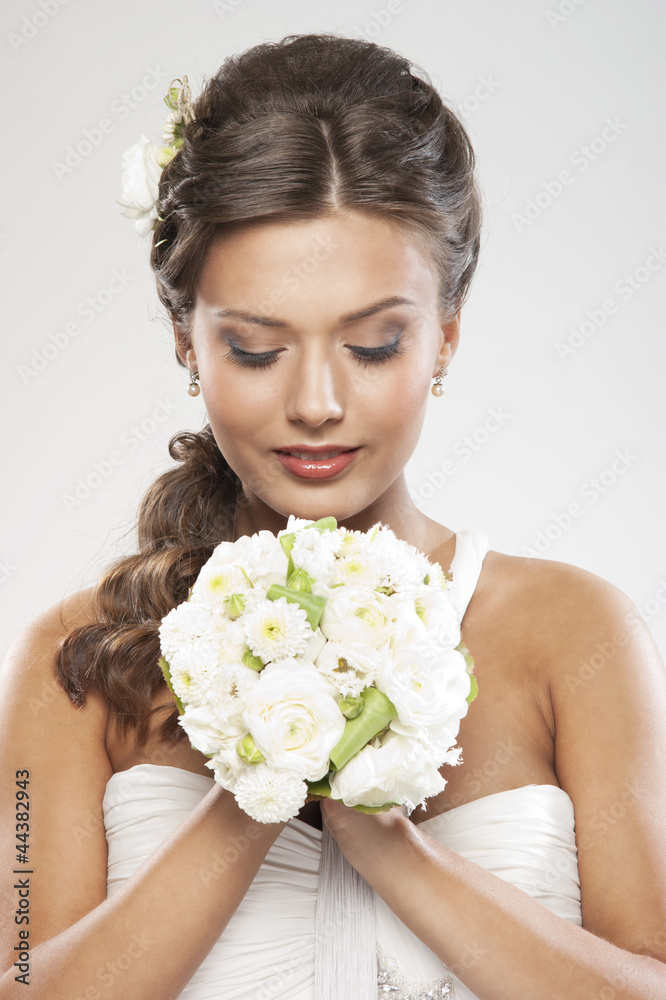 A young brunette bride holding a bouquet of white roses